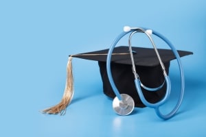 Graduation cap and a stethoscope against a light blue backdrop